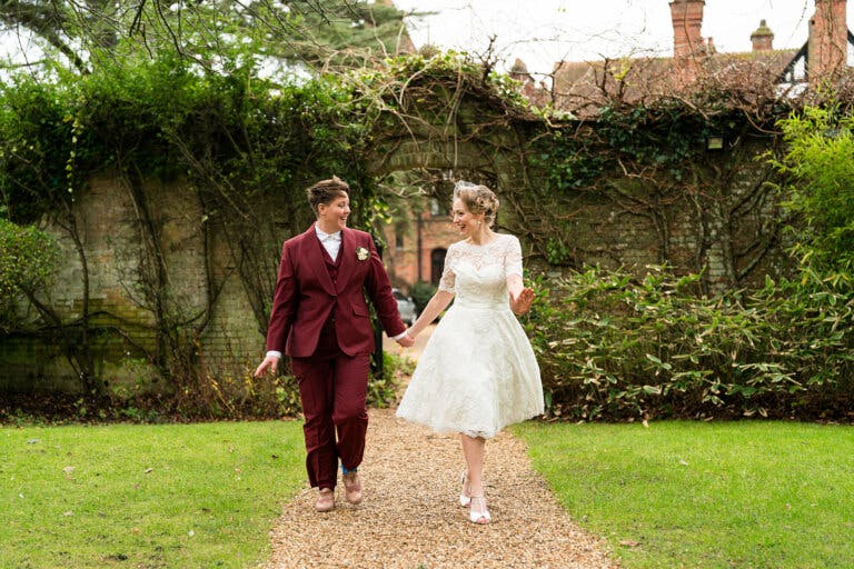 The couple walk hand in hand, smiling, through the hotel grounds