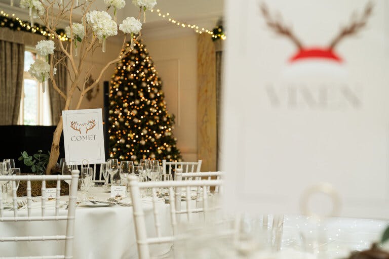 Image shows the Christmas tree in the Cedar Suite during the wedding breakfast with the tables and table name in the foreground out of focus