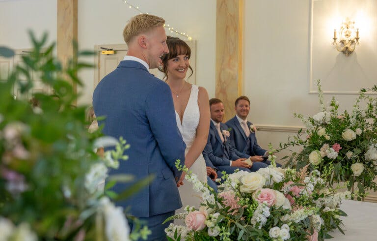 A close shot of the Bride & Groom standing side-by-side at the registrars table - smiling and look forward