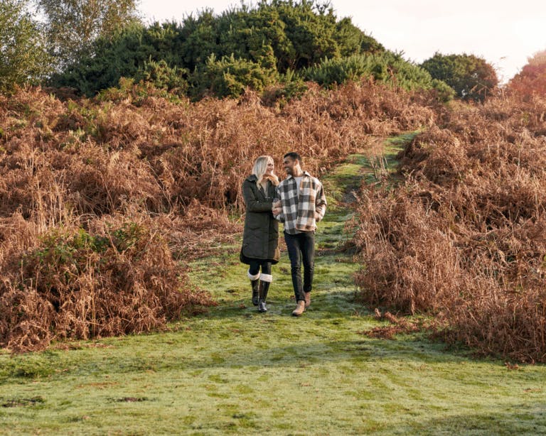 Autumn landscape in the New Forest with couple walking arm in arm in centre