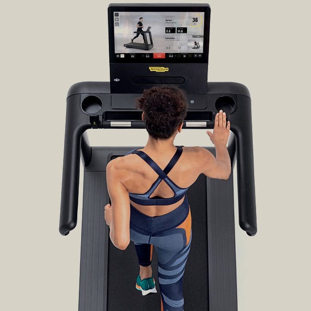 Woman runs on Technogym treadmill following programme