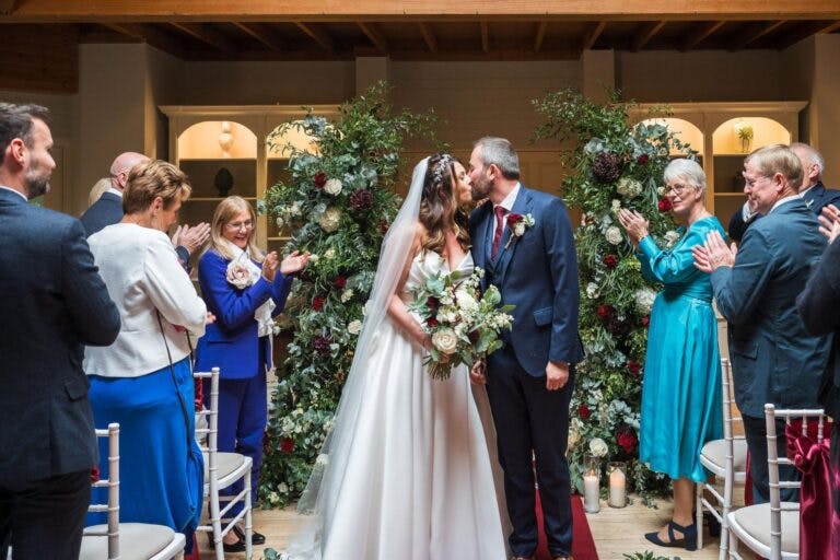 The bride and groom stop to kiss as walking up the aisle