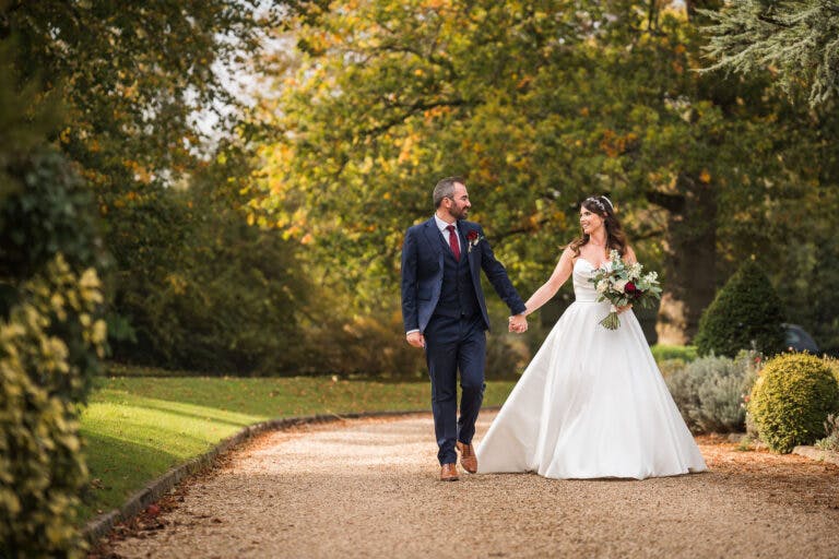 Bride and Groom Walk hand in hand in the garden