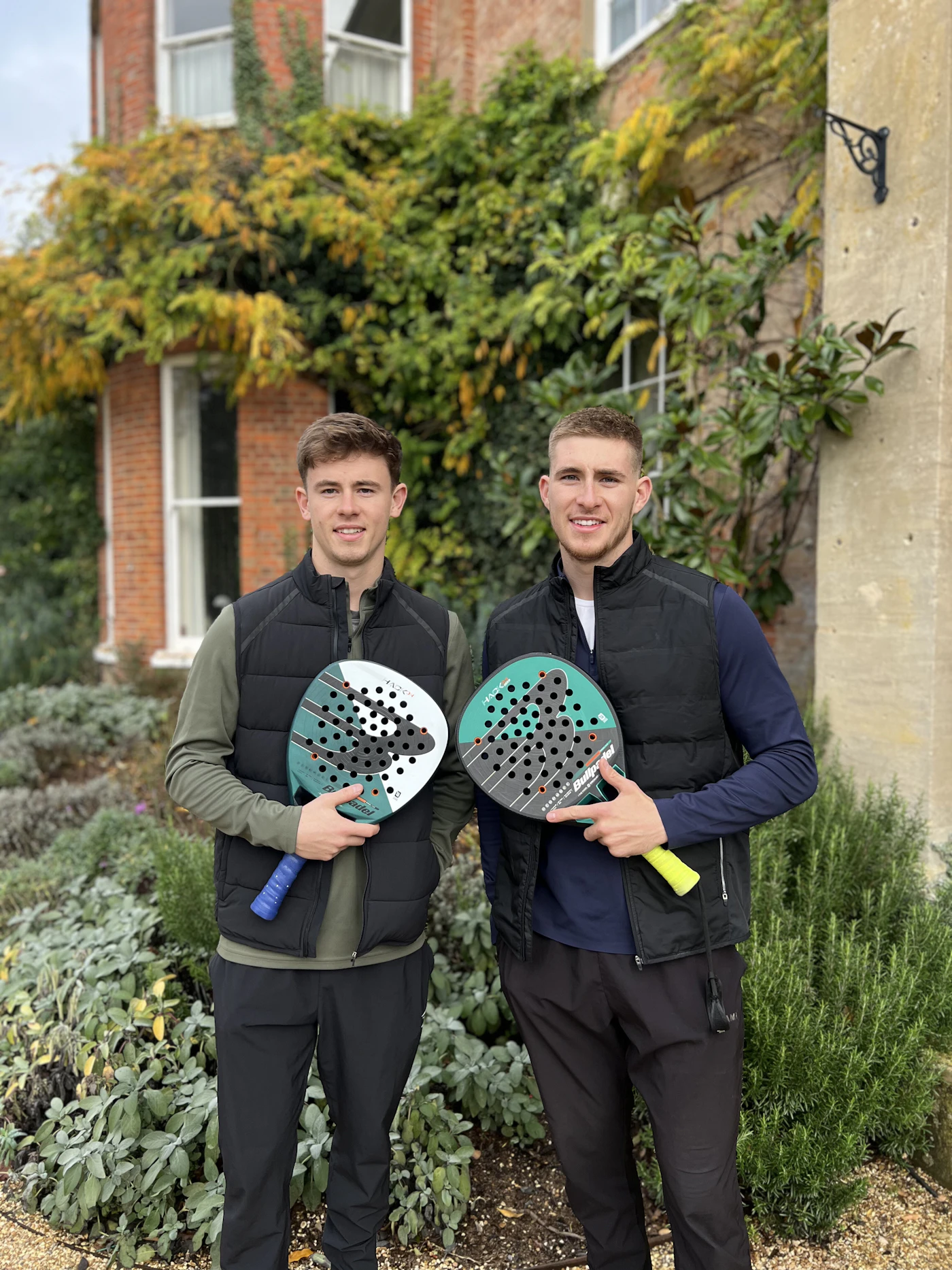 Two players with padel rackets in the gardens at The Retreat