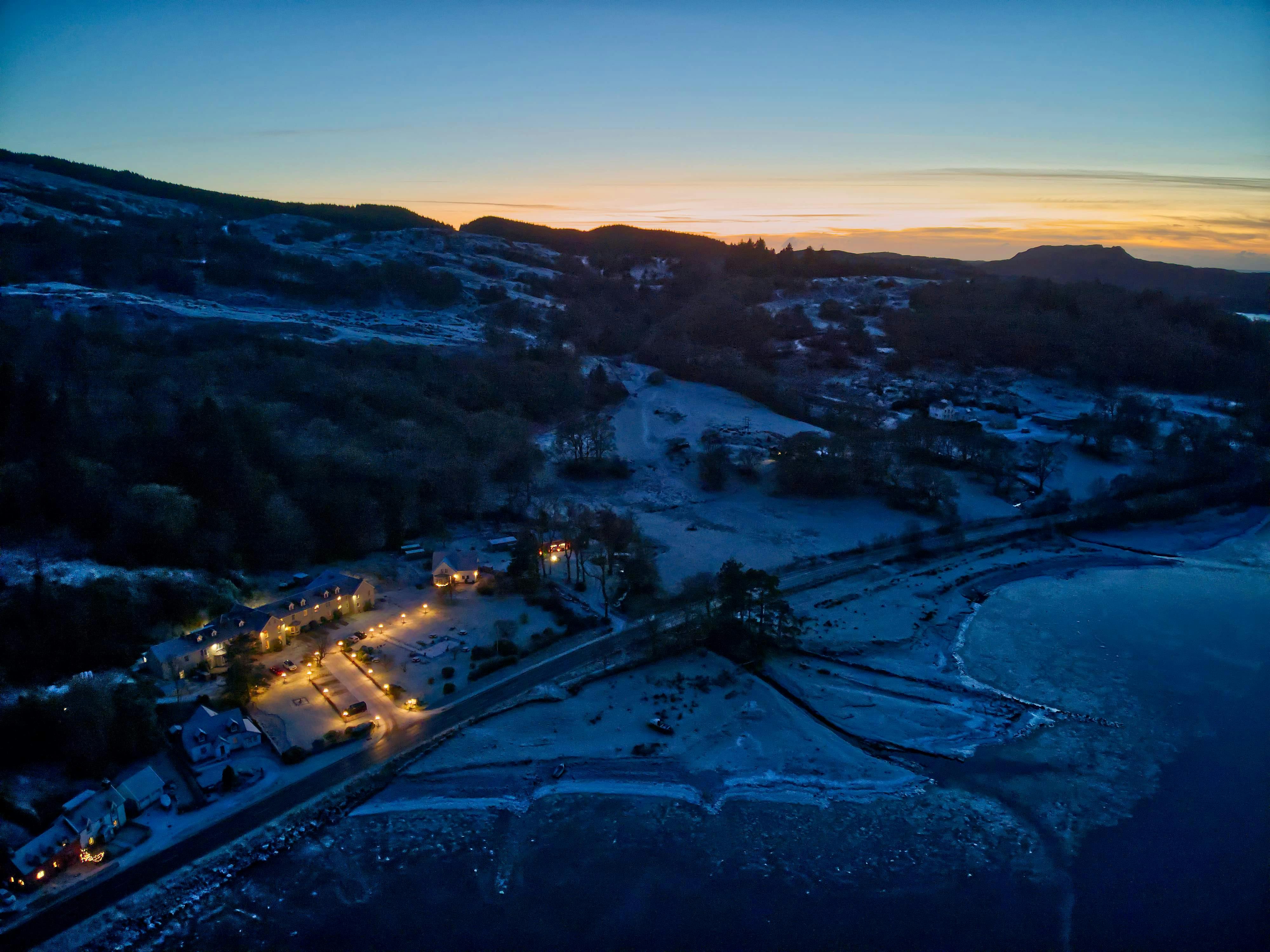 Picture of Knipoch house Hotel from above at nighttime with a sunset in the distance