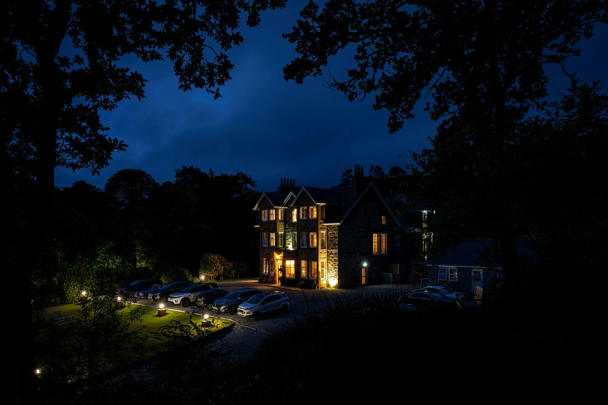 Duisdale House Hotel Nightime - cars parked outside the front, all light up by the outside lights