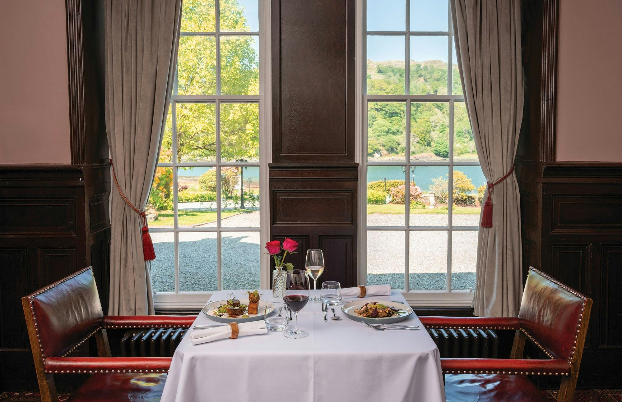 Knipoch house hotel dining set-up - bright windows - looking onto the water - wine and dinner on the table