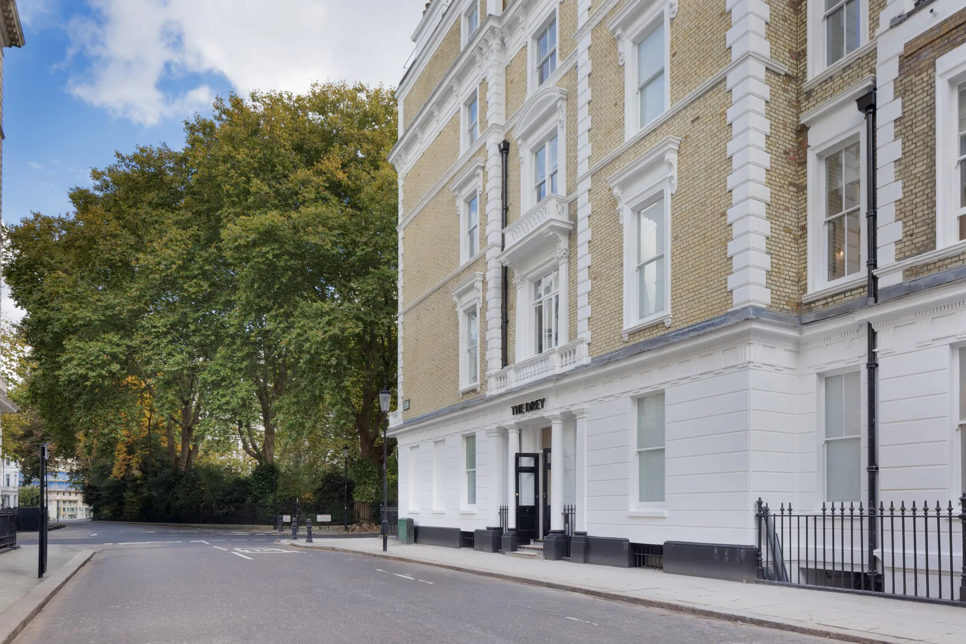 The Drey exterior on a quiet tree lined London street with cream brick buildings and white trim. Visible text reads "THE DREY".